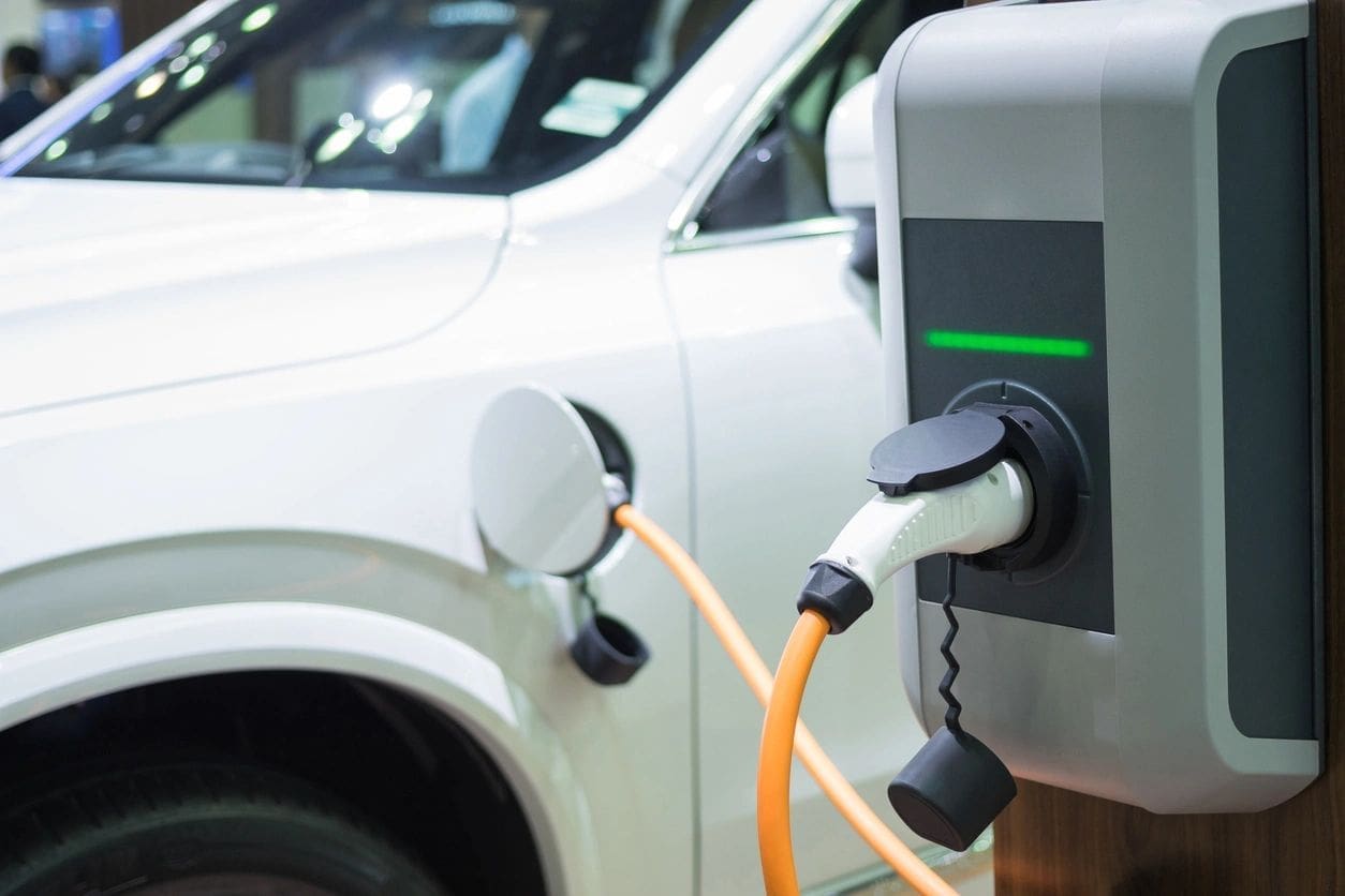 A white car is plugged into an electric vehicle charger.